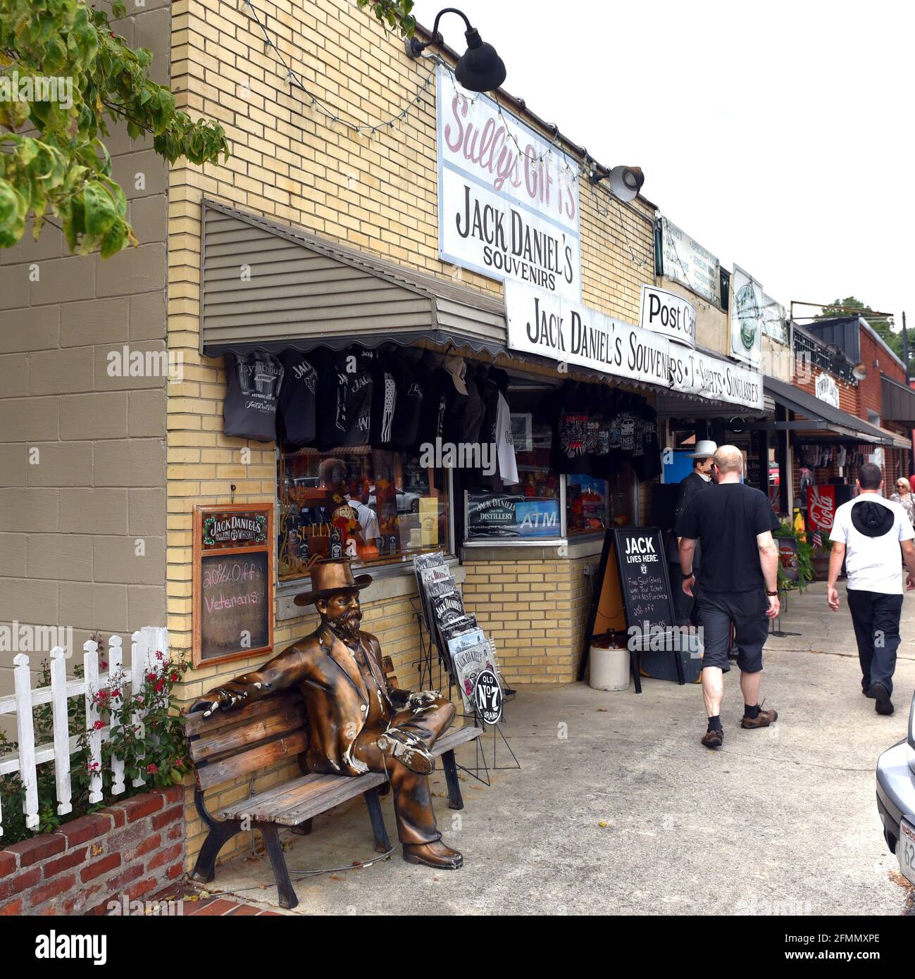 Lynchburg, TN, USA - 23. September 2019: Jack Daniel's Souvenirshop mit Statue von Daniel auf der Bank im traditionellen Handelsblock in der Nähe des Stockfoto