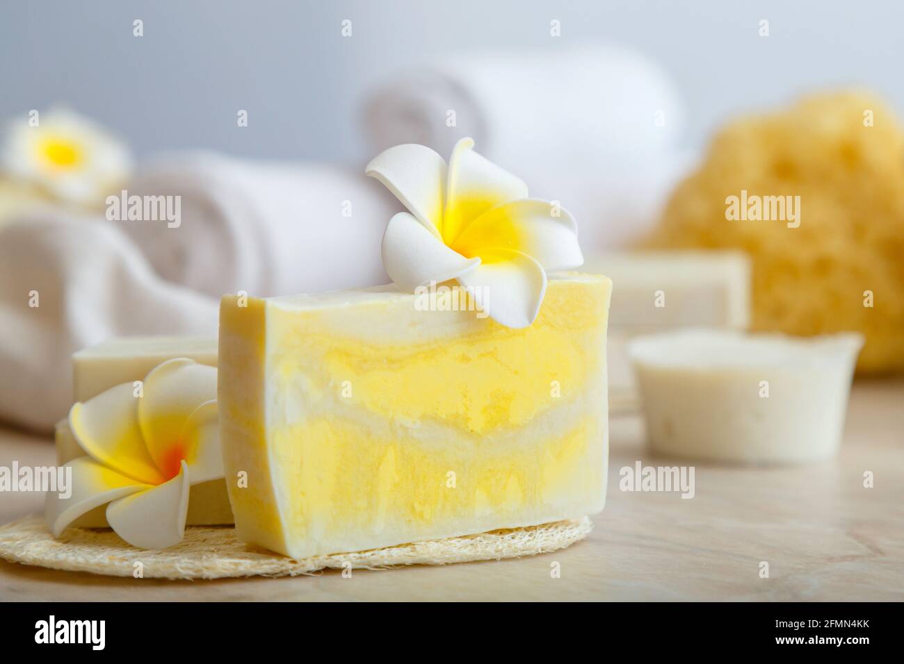 Handgemachte Seife, Spa-Badeprodukte weiße Handtücher tropische Plumeria Blumen auf Marmortisch im Badezimmer. Eco Beauty Kosmetik für Wellness Gesundheit Hautpflege. Stockfoto