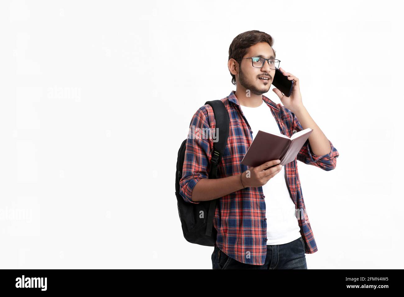 Indische College-Student im Gespräch auf dem Smartphone auf weißem Hintergrund. Stockfoto