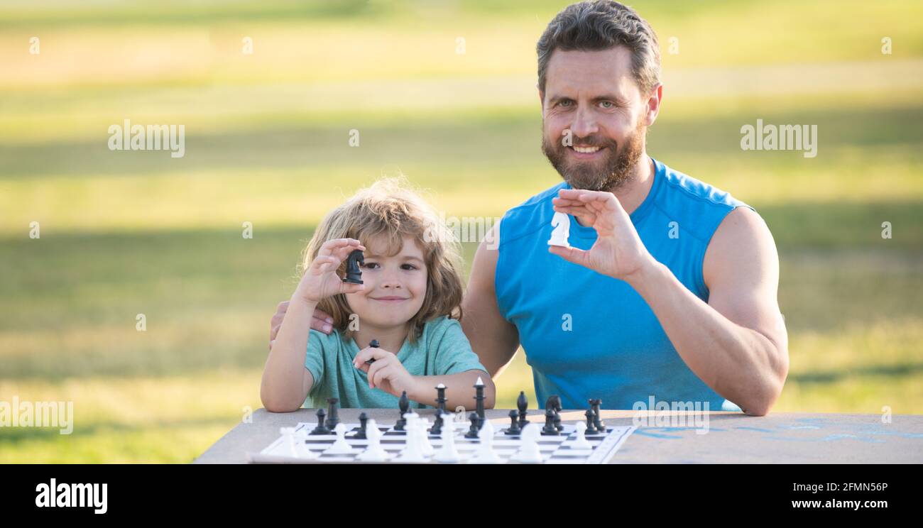 Sohn liegt auf Gras und spielt Schach mit Vater. Kind spielt Schach. Stockfoto