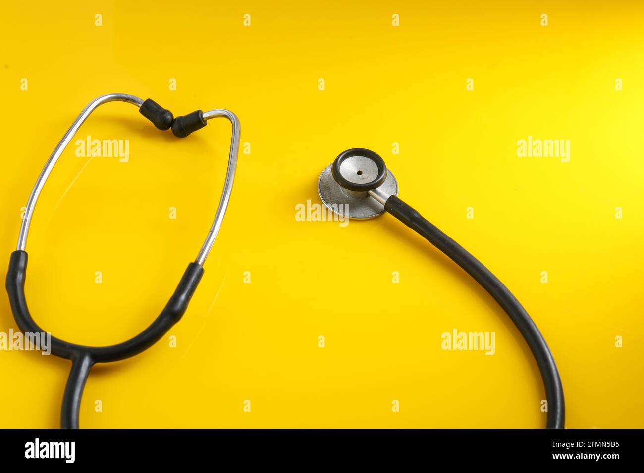 Ein Herz mit einem Stethoskop auf gelbem Hintergrund. Stockfoto