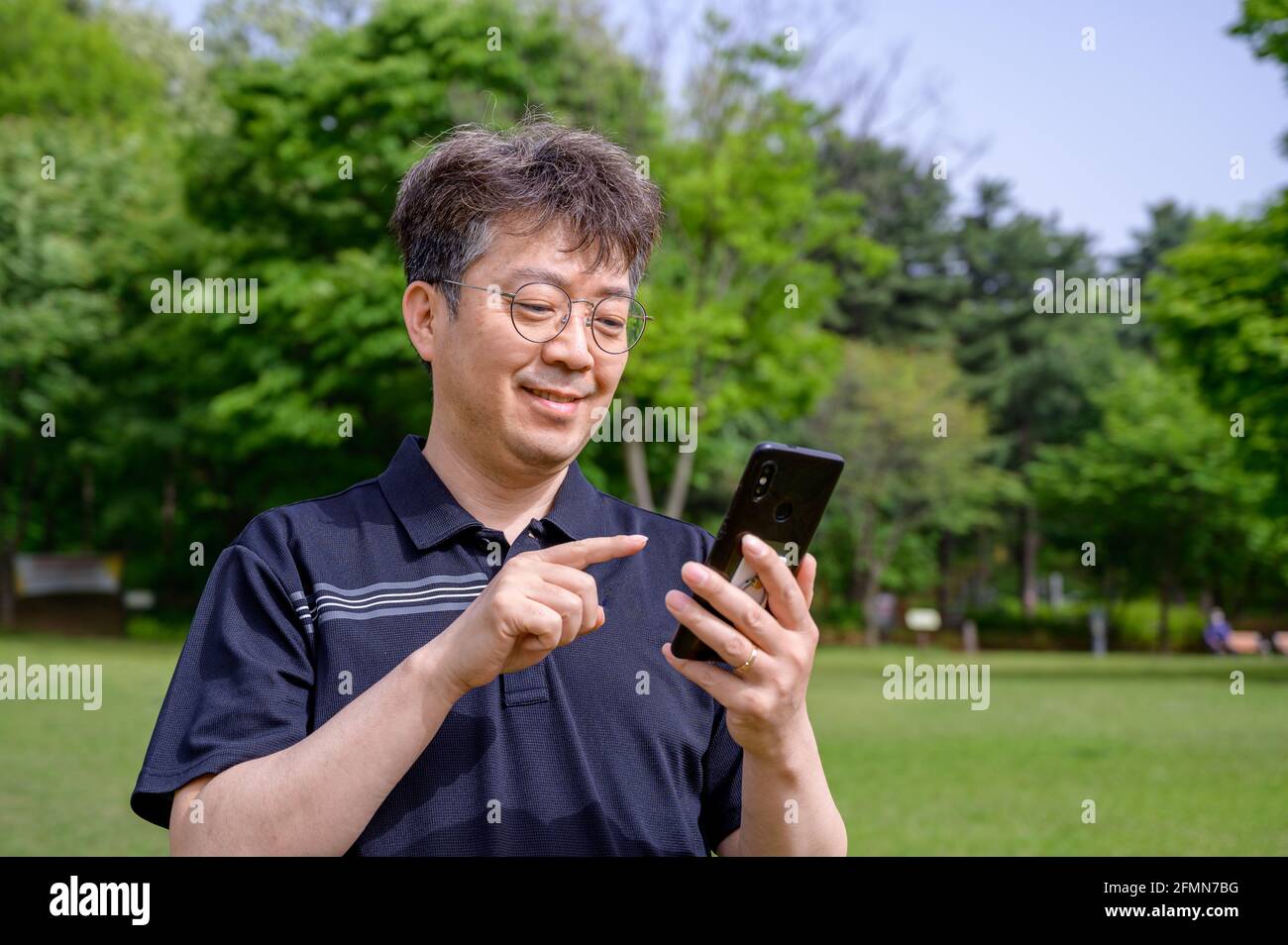 Mann mittleren Alters mit einem Smartphone auf dem Rasen. Stockfoto