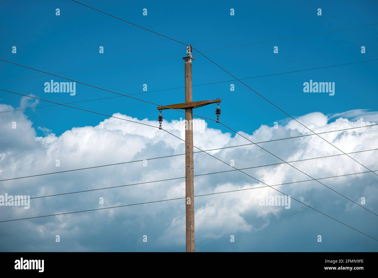 Betonstrommast mit Drähten gegen bewölkten Himmel im Hintergrund Stockfoto