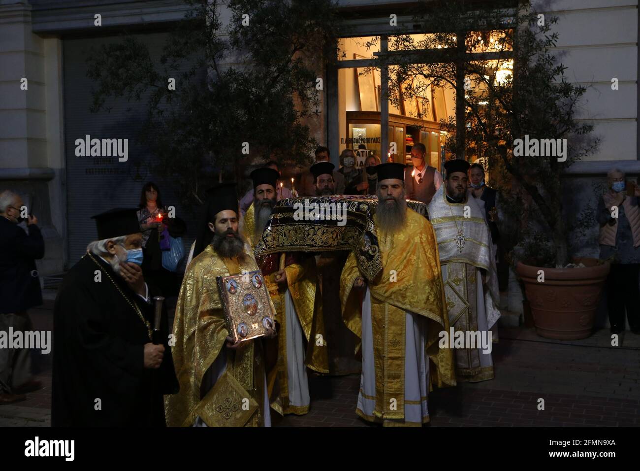 Griechisch-orthodoxe Priester halten während der Karfreitagsprozession des Epitaphios in der Kathedrale von Athen die Bahre hoch, die die Vorbereitung Christi auf die Beerdigung darstellt. Die Kirchen waren letzte Ostern geschlossen, dürfen aber für die diesjährigen Gottesdienste geöffnet bleiben, mit Sitzbeschränkungen und obligatorischer Verwendung von COVID-19-Testkits für Priester und Kirchenpersonal. Der Hauptgottesdienst am kommenden Samstag wird drei Stunden früher statt, um 9:00 Uhr aufgrund von Sperrmaßnahmen, während die Gläubigen werden von der Regierung geraten, im Freien zu bleiben. Stockfoto