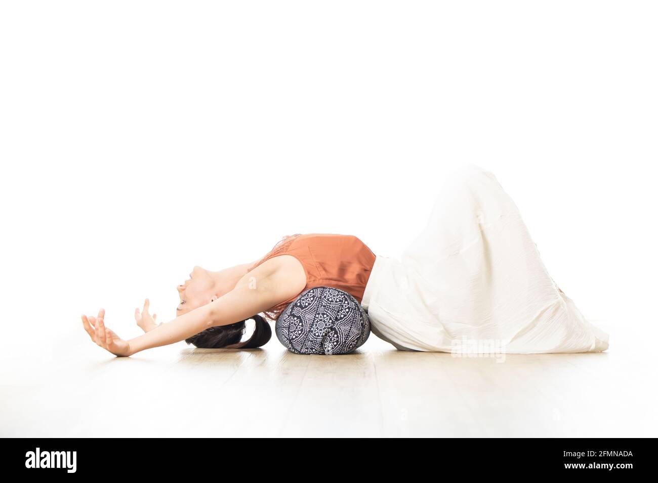 Erholendes Yoga mit einem Aufpolster. Junge sportliche attraktive Frau im leuchtend weißen Yoga-Studio, Stretching und Entspannung während erholsamem Yoga mit Stockfoto