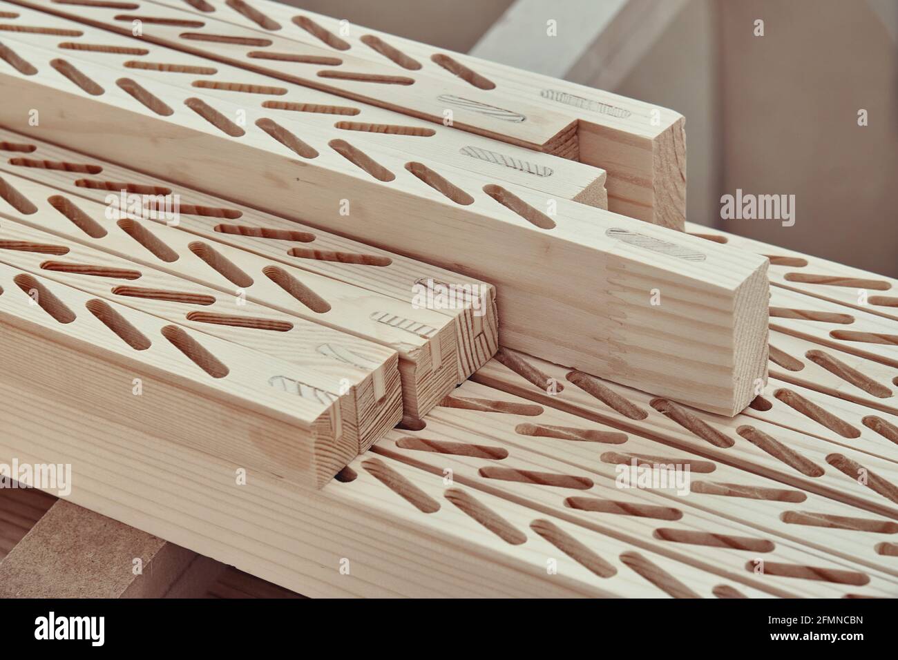 Neu bearbeitete Holzstäbe mit Linien von Schlitzen zu installieren Dünne Bretter liegen auf der Werkbank in der Nähe der leichten Schreinerei Stockfoto