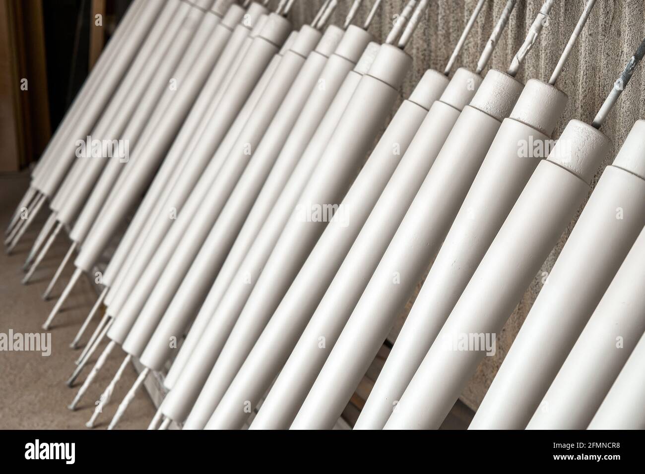 Die Sammlung der neuen hölzernen Möbelbeine trocknend nach dem Auftragen der Farbe Lehnte sich auf ein großes Regal in der hellen Holzwerkstatt extrem nah Anzeigen Stockfoto