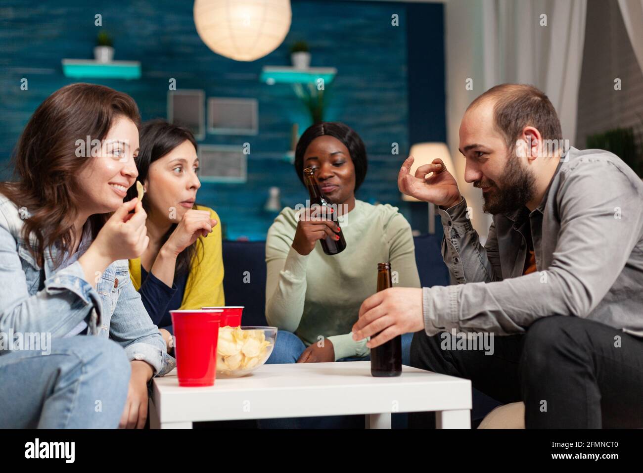 afroamerikanische Frau, die Spaß mit multiethnischen Freunden hat. Gruppe von multirassischen Menschen verbringen Zeit zusammen sitzen auf Couch spät in der Nacht im Wohnzimmer. Stockfoto