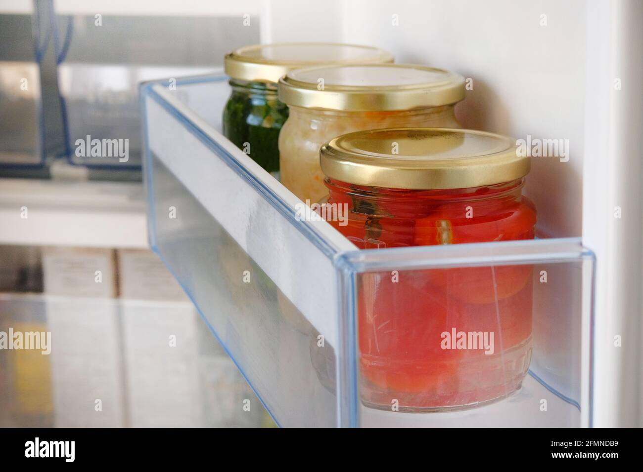 Gläser mit verschiedenen hausgemachten eingelegten Gemüse stehen im Kühlschrank. Fermentierte gesunde natürliche Ernährung Konzept. Seitenansicht. Stockfoto