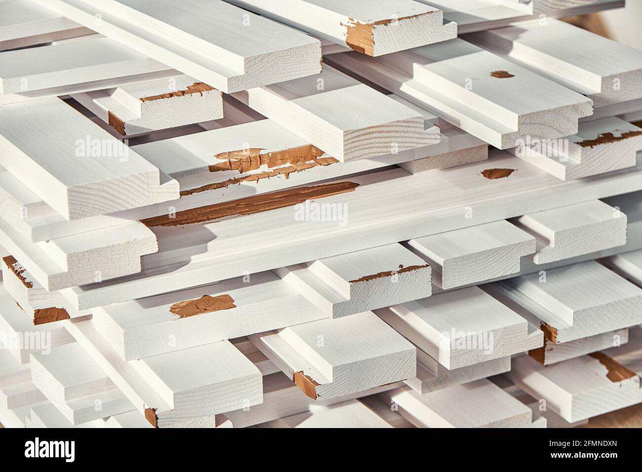 Stapel von Holzstäben aus massiver Kiefer in weißer Farbe Mit braunem Kitt liegen auf der Werkbank extreme Nahaufnahme Stockfoto