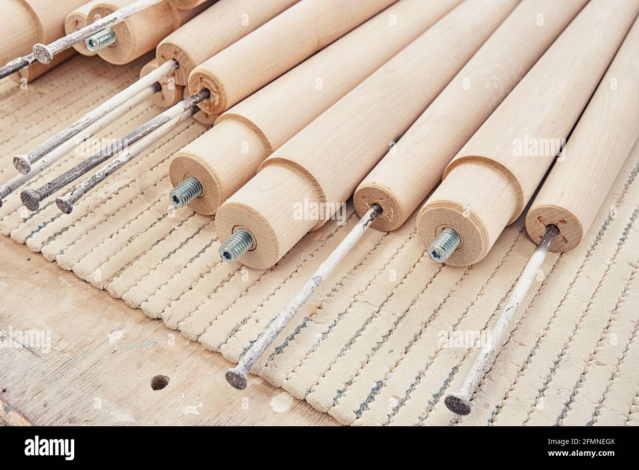 Drehen Sie die Holzbeine aus massiver Birke mit integriertem Schraubbolzen Und Nägel auf der Werkbank in Nahaufnahme gefaltet Stockfoto