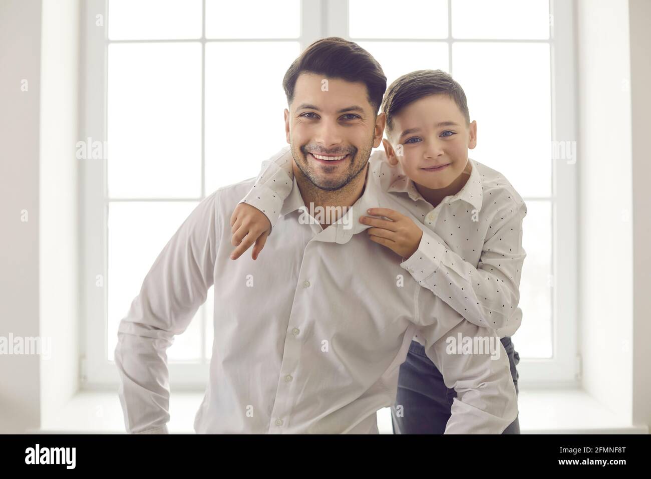 Nahaufnahme Porträt von niedlichen Vater mit kleinen Sohn umarmt und Blick gegen Fenster Hintergrund. Stockfoto
