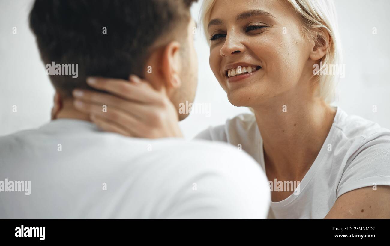 Fröhliche blonde Frau umarmt Freund auf verschwommenem Vordergrund Stockfoto