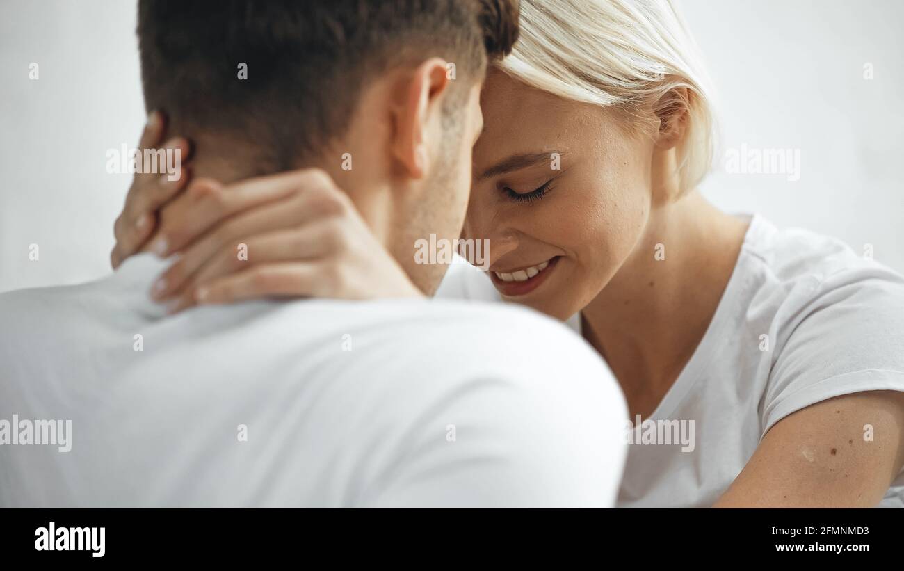 Glückliche blonde Frau umarmt Freund auf verschwommenem Vordergrund Stockfoto