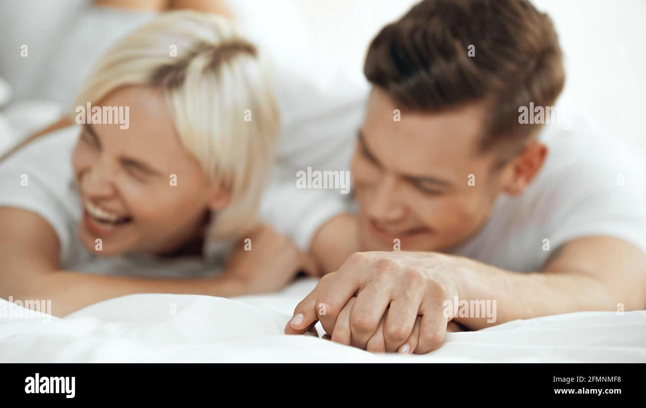 Verschwommene junge Frau und Mann halten die Hände fest und lachen hinein Bett Stockfoto
