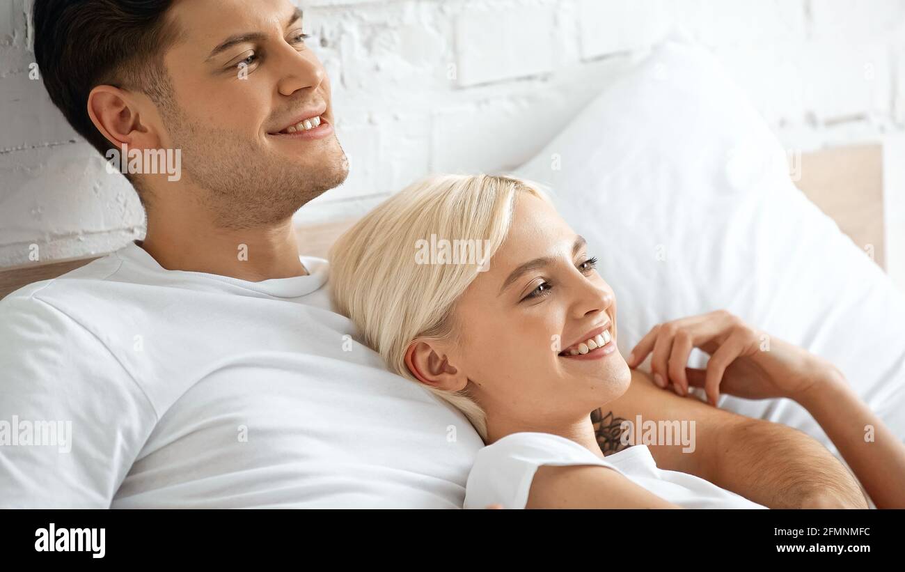 Tätowierte Mann, der mit einer angefreuten blonden Frau im Bett lag Stockfoto