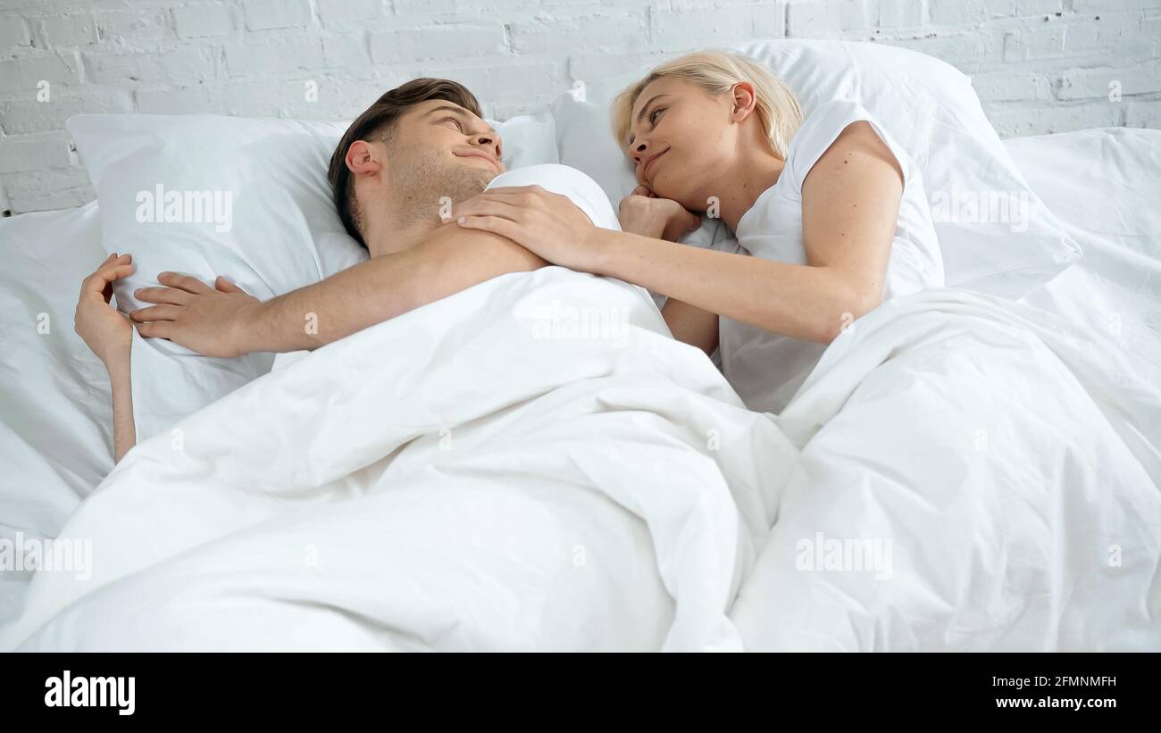 Junge Frau und Mann liegen im Bett und schauen zu Einander Stockfoto