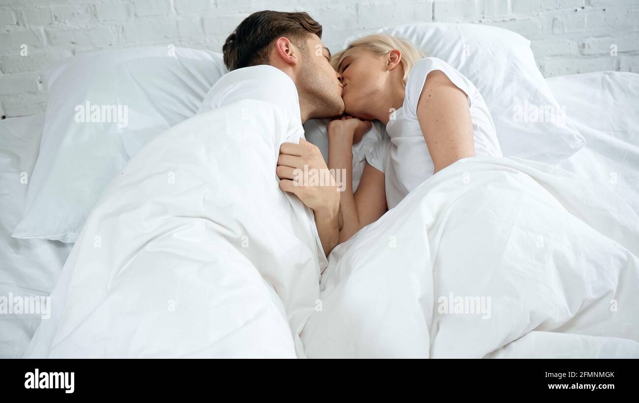 Junge Frau und Mann küssen sich im Bett Stockfoto