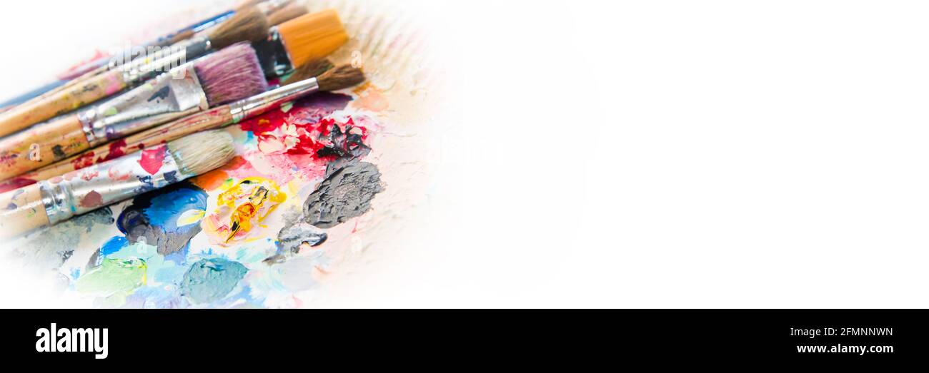 Verwendete Pinsel auf einer bunten Malerpalette. Paint Concept Panorama Hintergrund Stockfoto