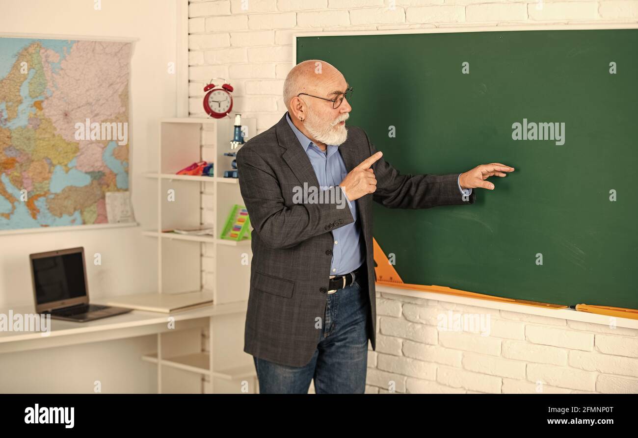 Oberlehrer erklären Thema an der Tafel. Lehrer für Geographie. Klassenzimmer mit Karte. Zurück zur Schule. Bildung in der modernen Schule. Bärtiger Mann zeigen Stockfoto
