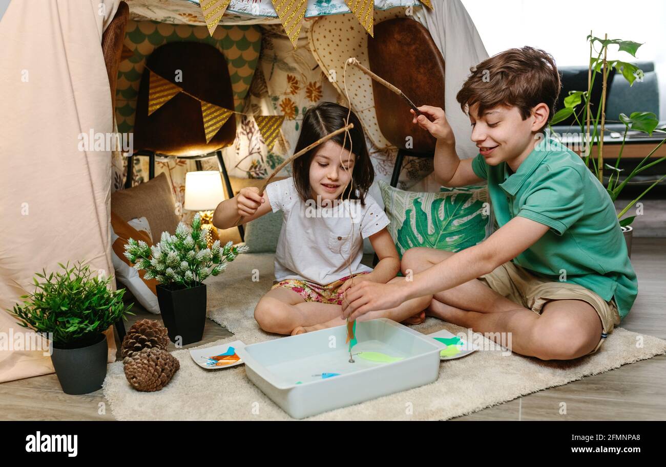 Glückliche Kinder, die zu Hause campen und Angelspiele spielen Stockfoto