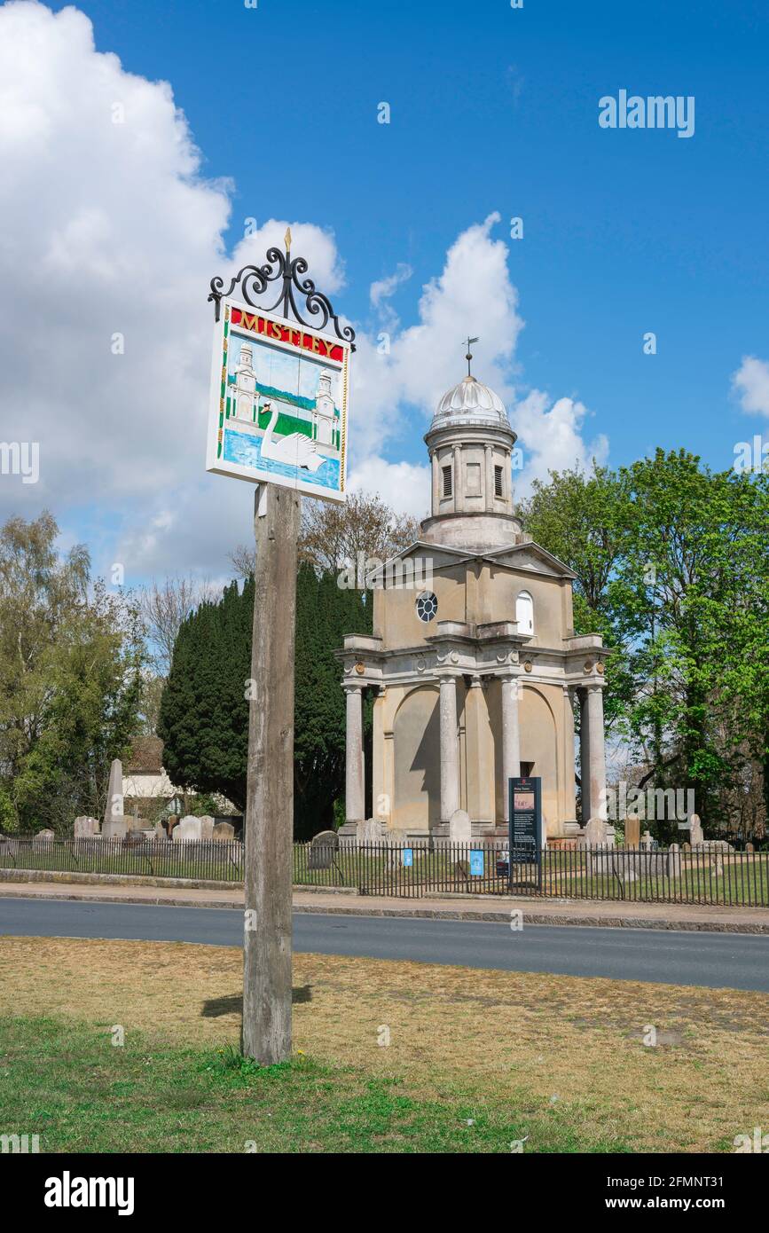 Mistley England, Blick auf das Dorfschild von Mistley auf dem Grün mit einem der beiden von Robert Adam entworfenen Türme aus dem Jahr 1776 Visible, Essex, Großbritannien Stockfoto