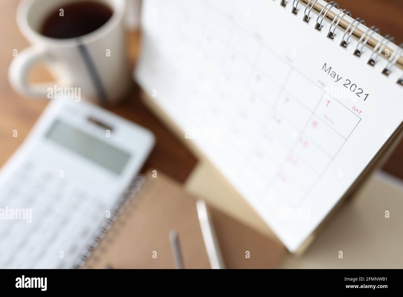 Kalender aus Papier mit losen Blättern, der auf dem Tisch neben dem Rechner und der Tasse steht Von Kaffee aus der Nähe Stockfoto