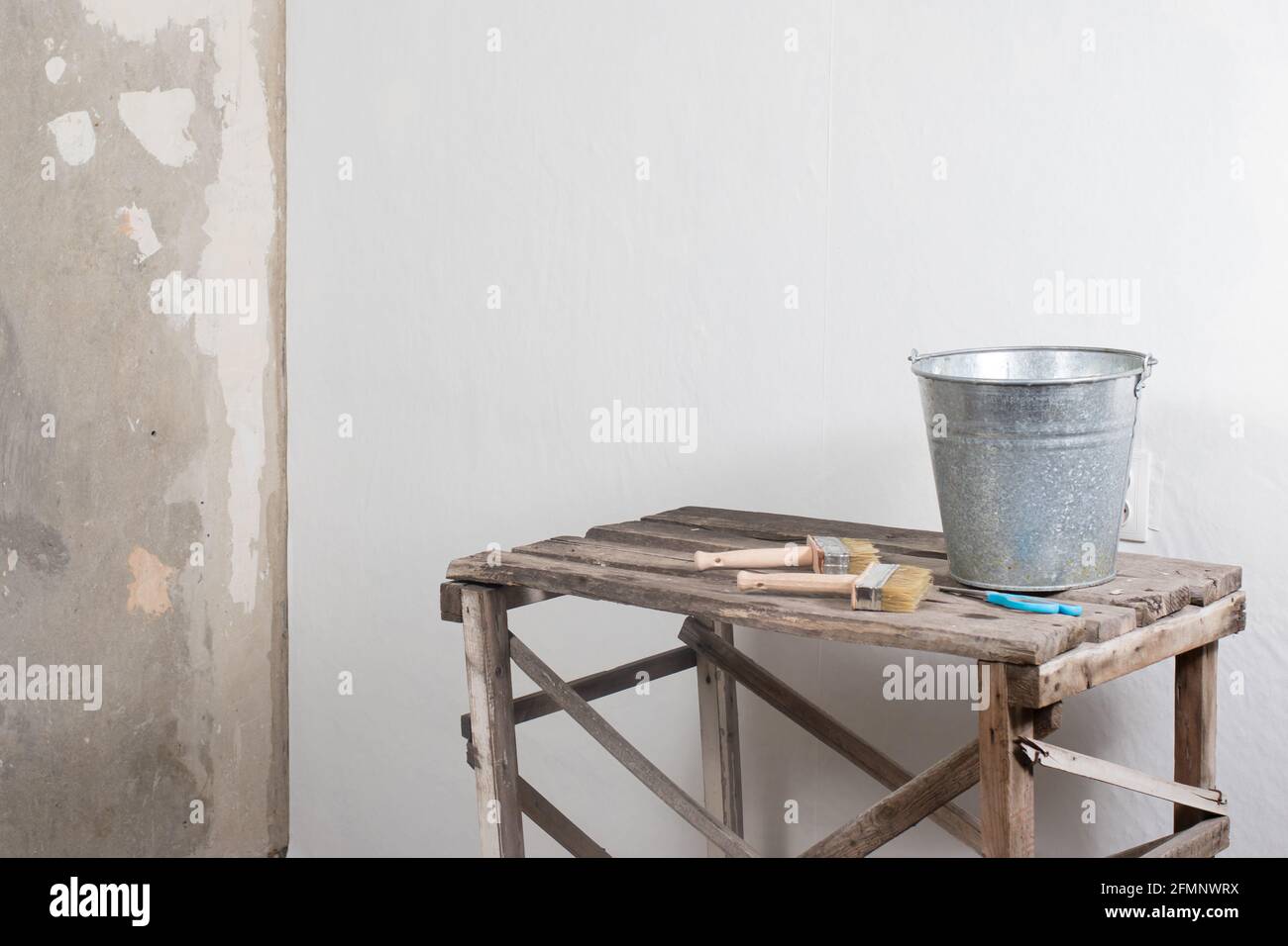 Der Prozess der klebenden weißen Tapete, ein Eimer mit Klebstoff. Mit einem Ort für Text. Bau und Reparatur Stockfoto