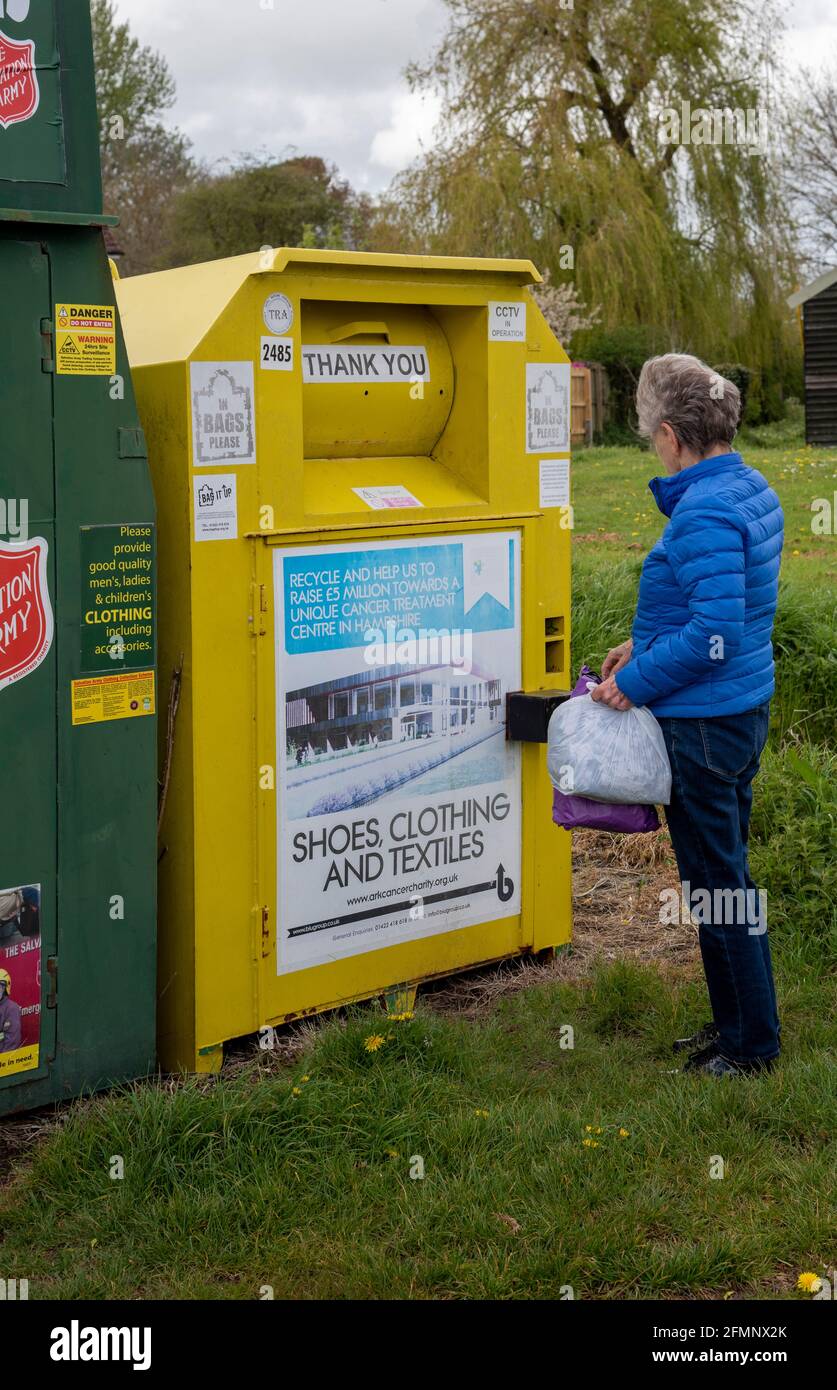 Hampshire, England, Großbritannien. 2021. Frau spendet Kleidung für wohltätige Zwecke, indem sie einen Sammelbehälter für gemeinnützige Zwecke in einem Dorf in Hampshire verwendet. Stockfoto