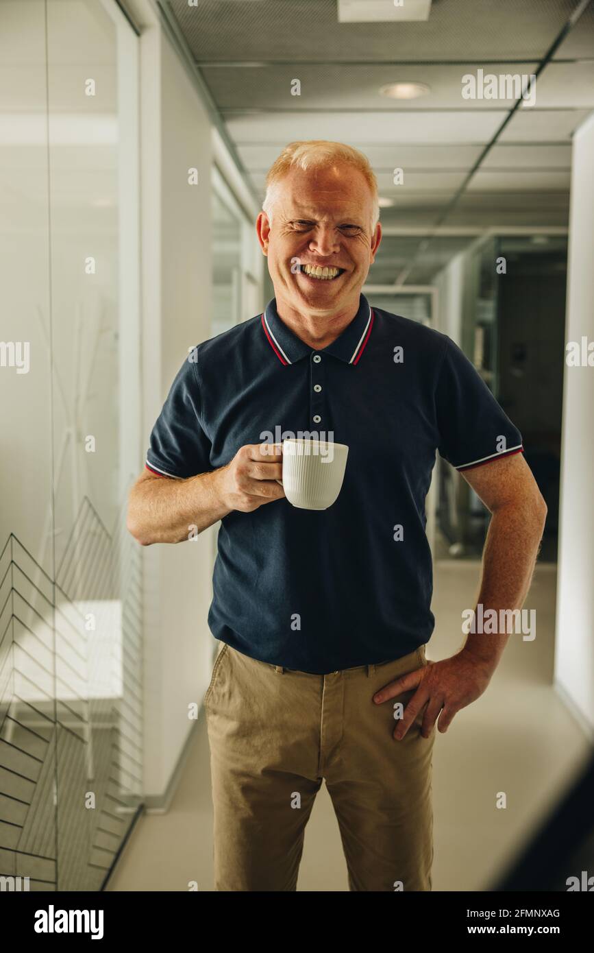 Glücklicher Geschäftsmann beim Kaffee. Männlicher Manager, der eine Kaffeepause im Büro hat. Stockfoto