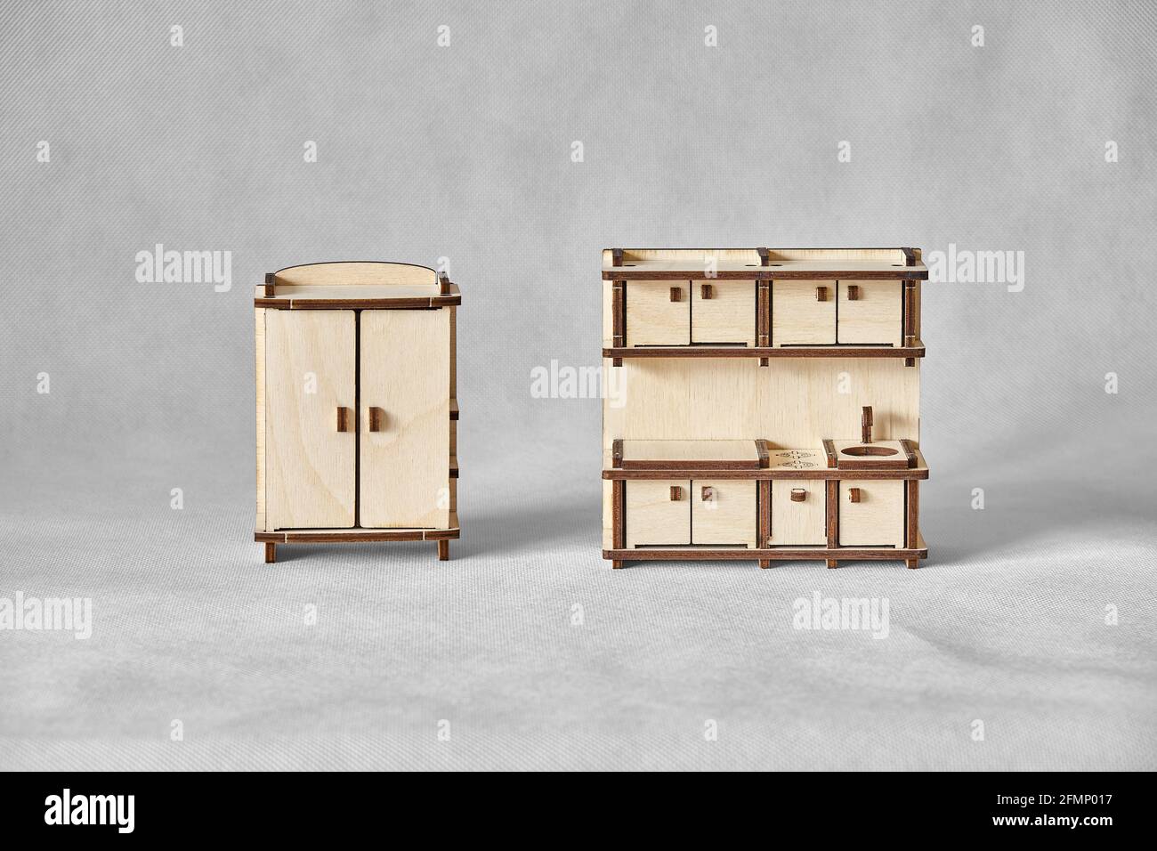 Niedliche kleine Spielzeug Garderobe und Küche Set aus Ply Holzdetails mit Laser-Werkzeugmaschine geschnitten stehen auf Licht Grauer Hintergrund Stockfoto