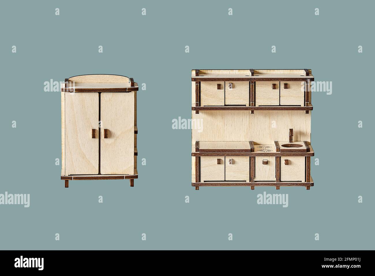 Niedliche kleine Spielzeug Garderobe und Küche Set aus Ply Holzdetails geschnitten mit Laser-Werkzeugmaschinen isoliert auf grün Hintergrund Stockfoto