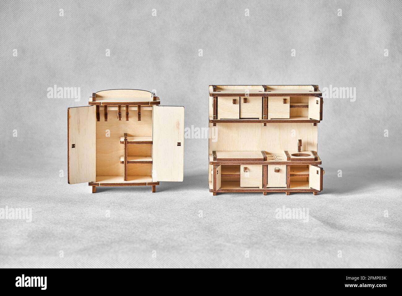 Niedliche kleine Spielzeug Garderobe und Küche Set aus Ply Holzdetails mit Laser-Werkzeugmaschine geschnitten stehen auf Licht Grauer Hintergrund Stockfoto