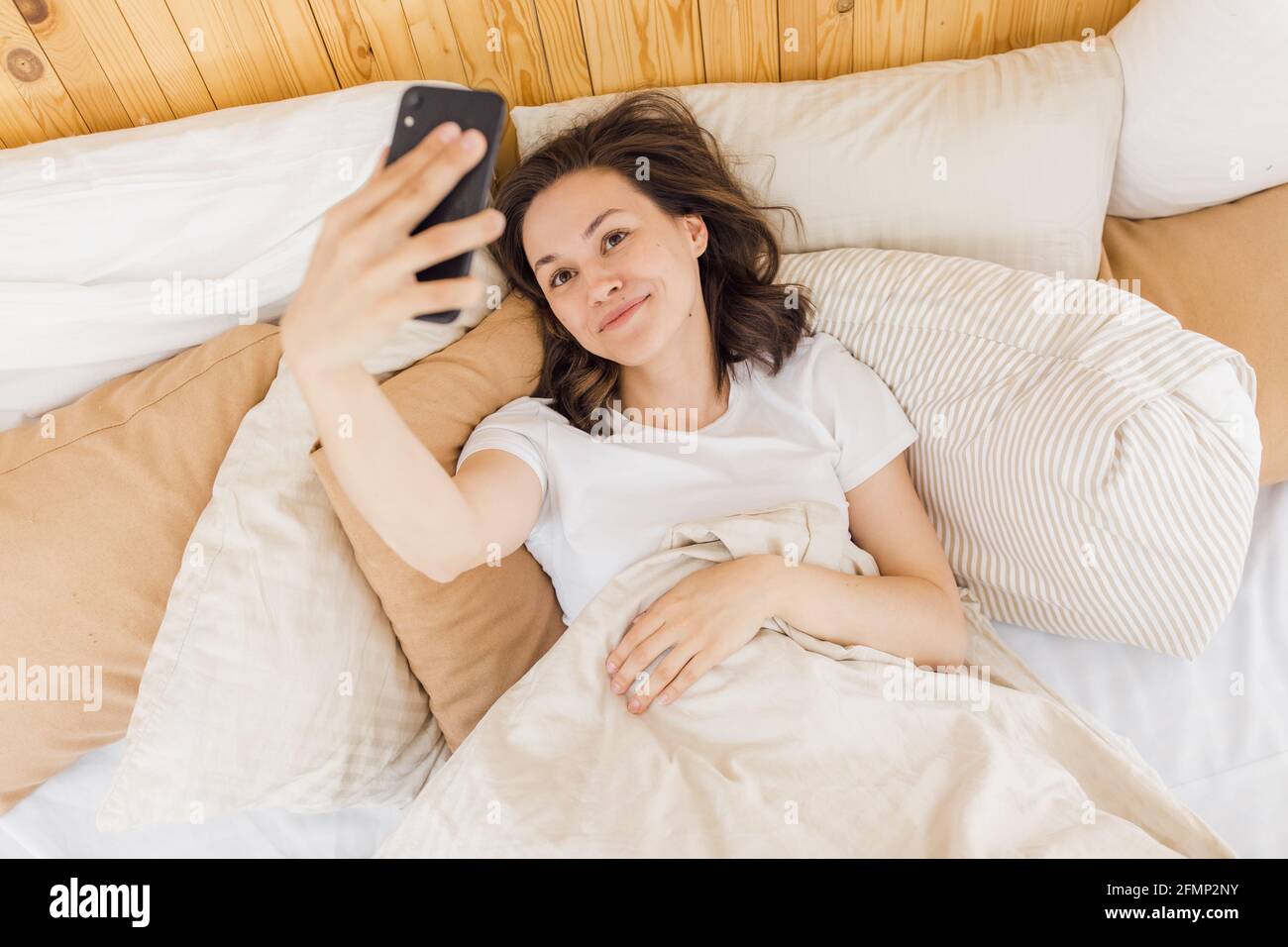 Junge attraktive Frau nimmt ein Selfie kurz nach dem Aufwachen Stockfoto
