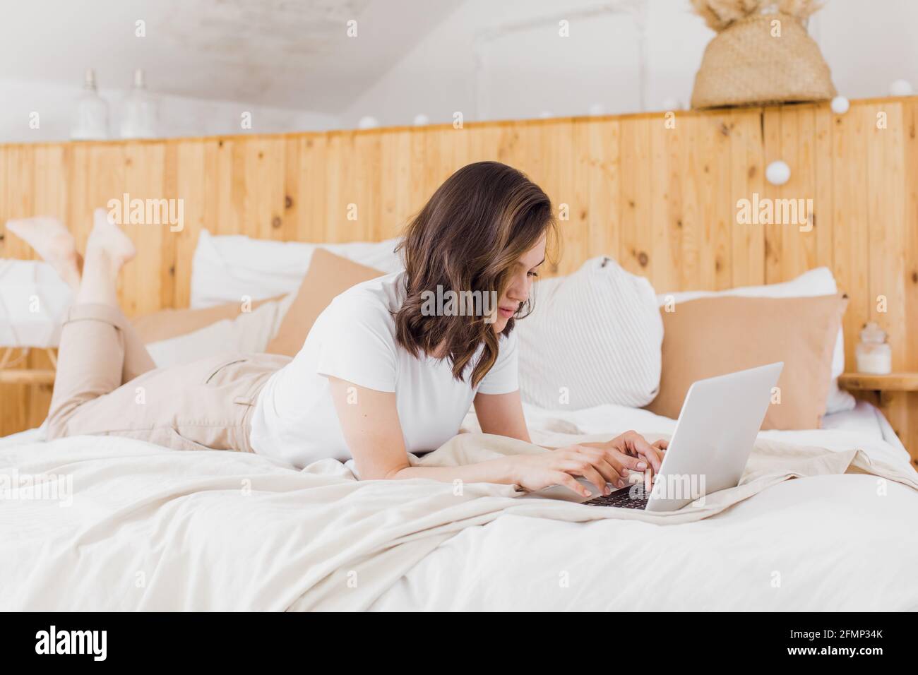 Frau, Die Sich Auf Dem Bett Entspannt Und Den Laptop Für Videoanrufe Benutzt In moderner Wohnung Stockfoto