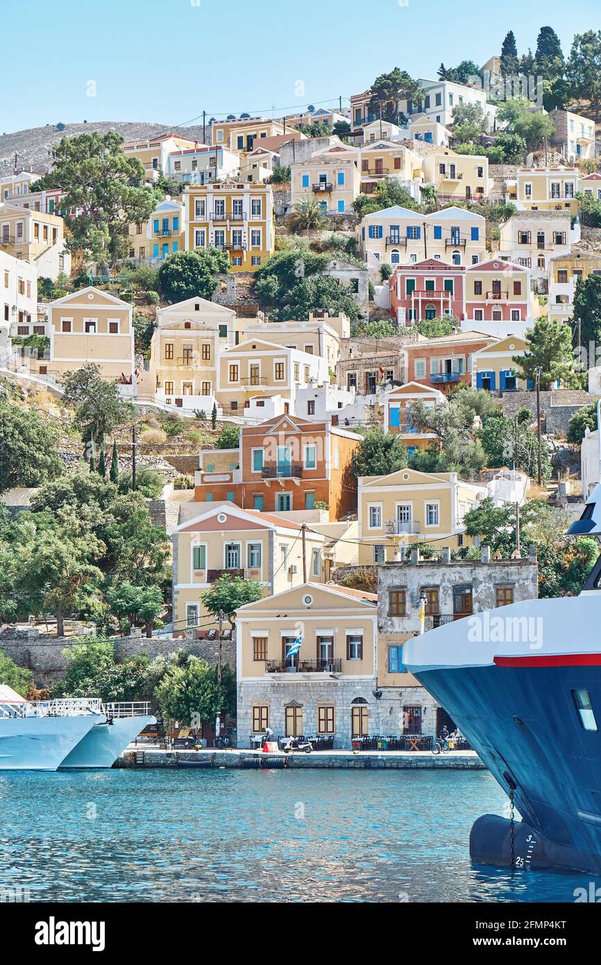 Große Jacht auf dem Meer vor der historischen Stadt mit alten festgemacht Bunte Gebäude auf Hügeln auf Symi Insel in Griechenland verstreut Stockfoto
