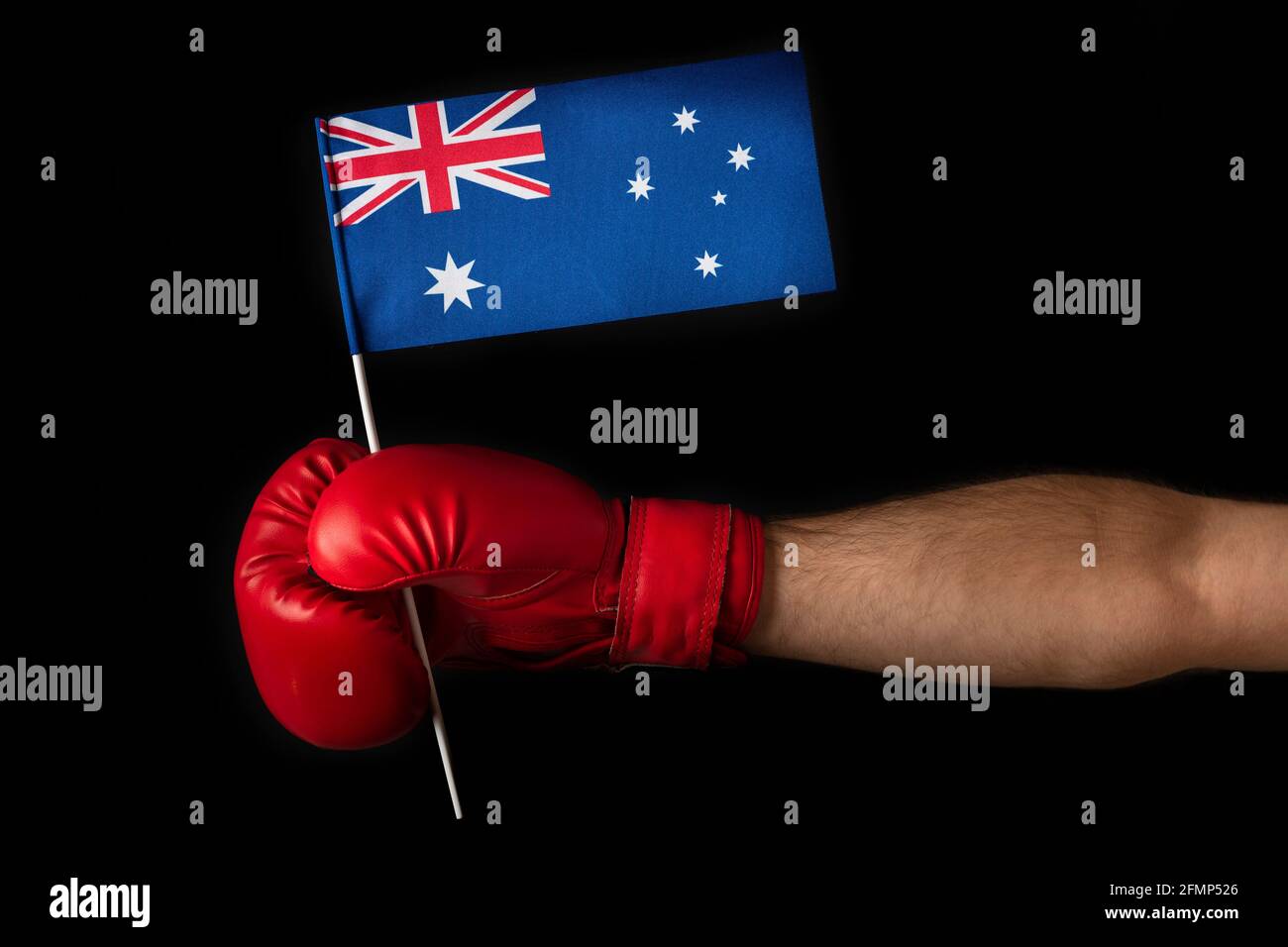 Hand in Boxhandschuh hält die australische Flagge. Schwarzer Hintergrund Stockfoto