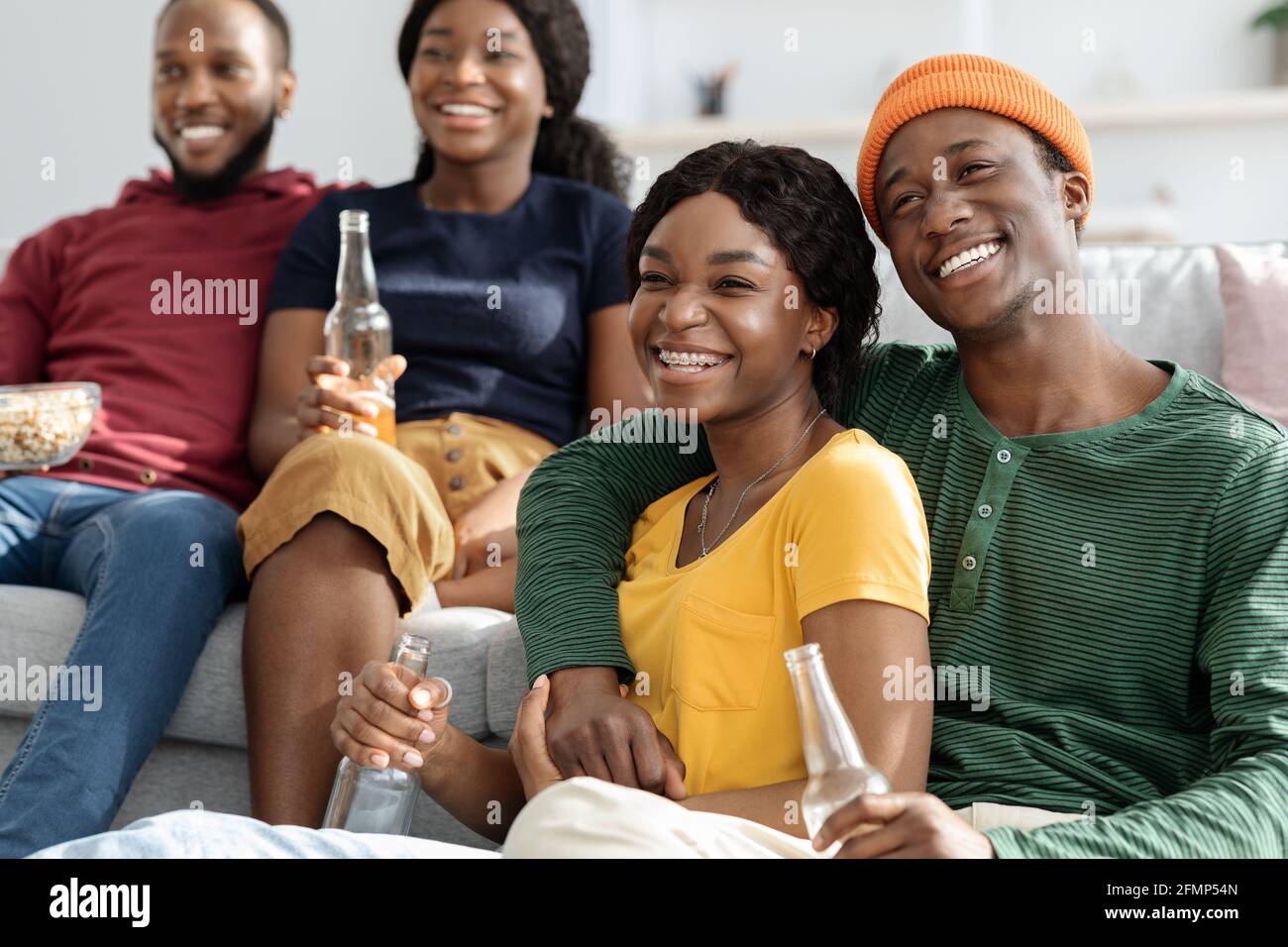 Fröhliche afroamerikanische Paare genießen Film zu Hause Stockfoto