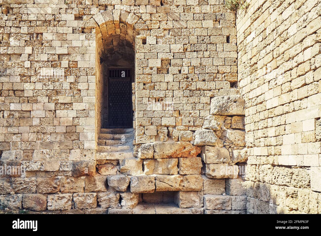 Verwitterte alte Rhodos Festung Ziegel und Steinmauer mit leer Bogen Tür unter hellem Sonnenlicht im Sommer Griechenland Stockfoto