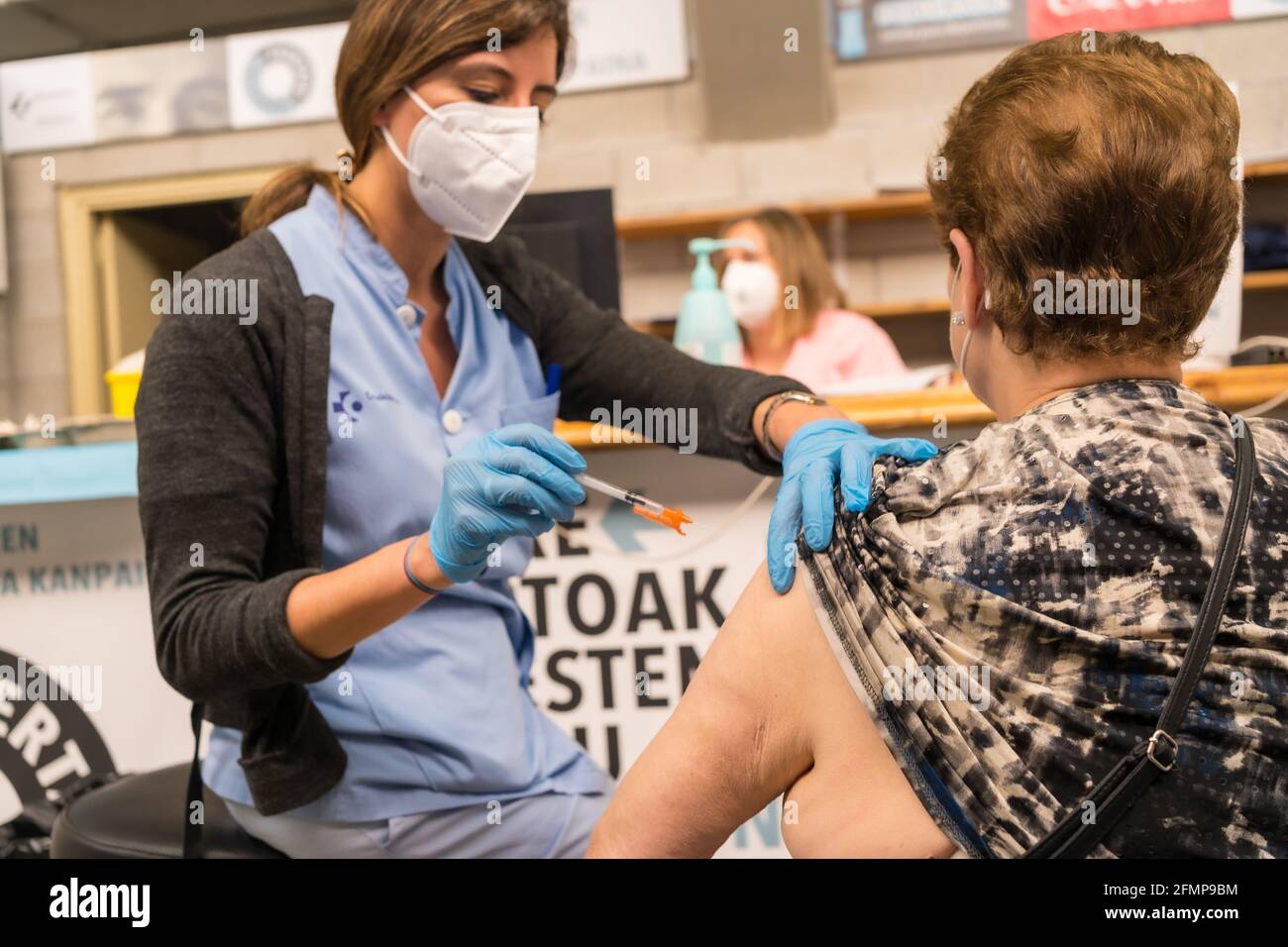 SAN Sebastián, SPANIEN – 08. Mai 2021: Eine ältere Frau erhält die Injektion der Dosis von einer jungen Krankenschwester im Impfzentrum Covid-19. Corona Stockfoto