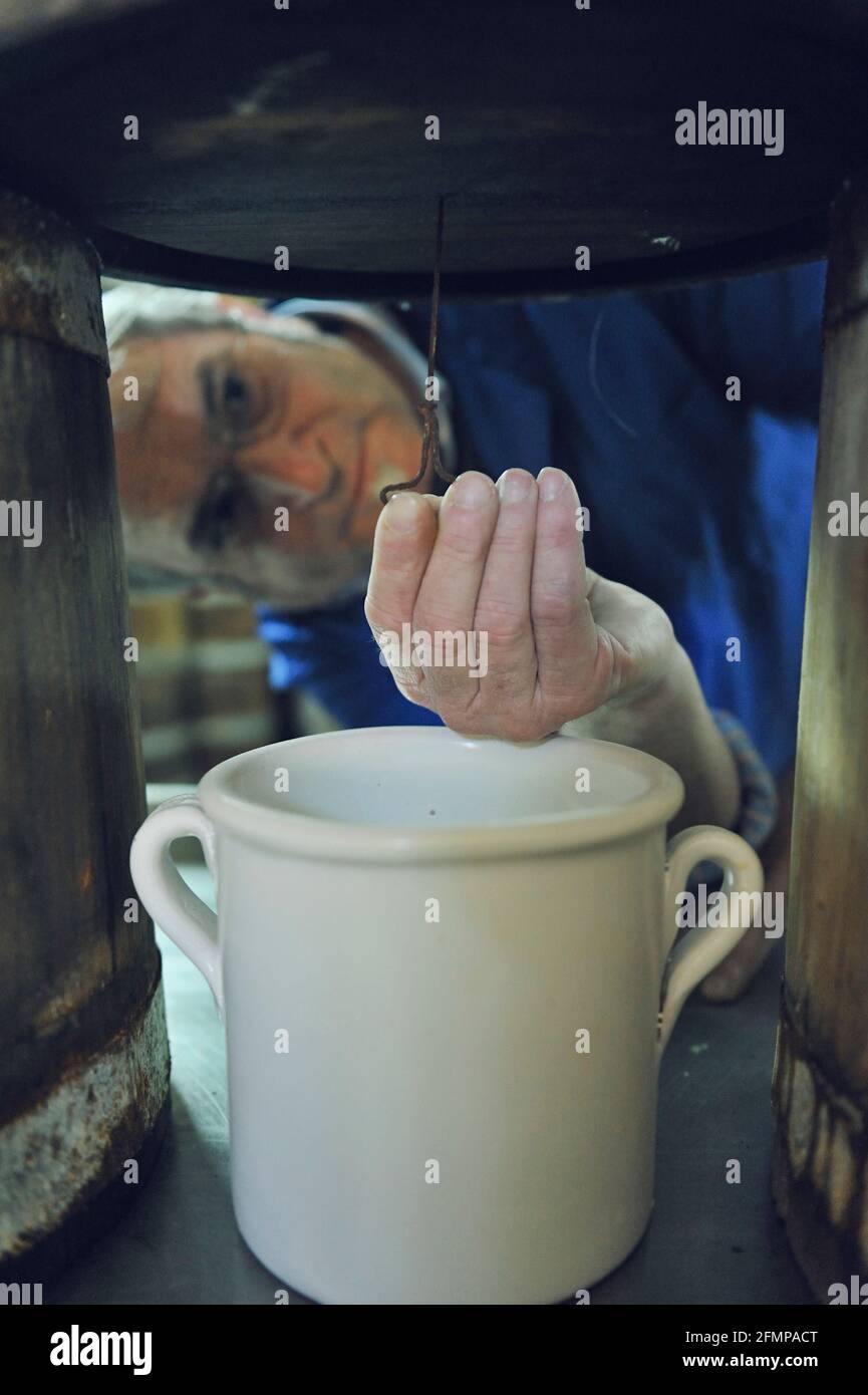 Battista, Fischer und Inhaber der Firma 'Delfino', die Öl und gesalzene Sardellen, Thunfisch und die berühmte Sardellensoße herstellt, macht ein Loch in Th Stockfoto