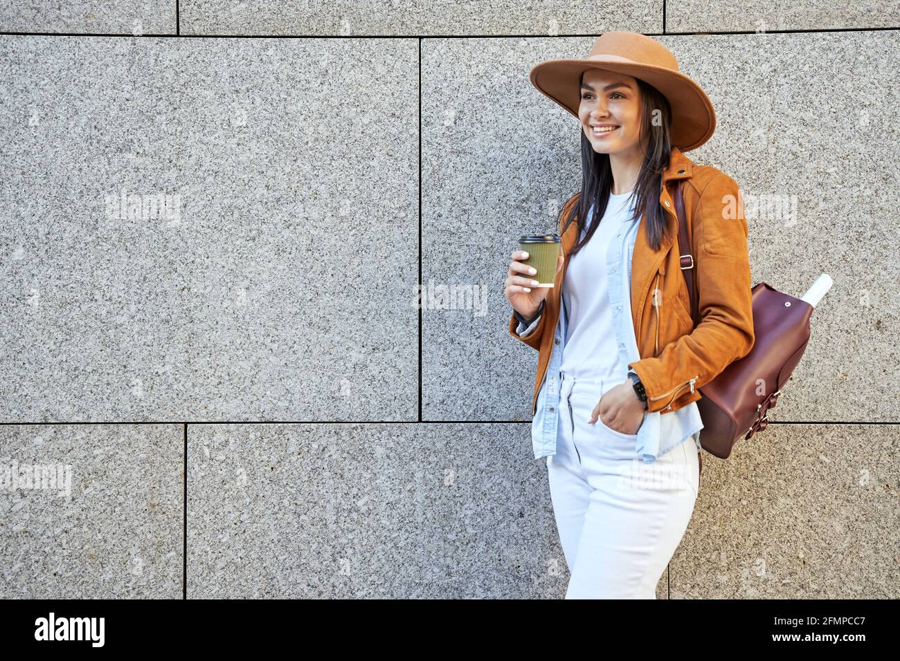 Ziemlich stilvolle Dame mit Rucksack posiert mit heißem Getränk Stockfoto