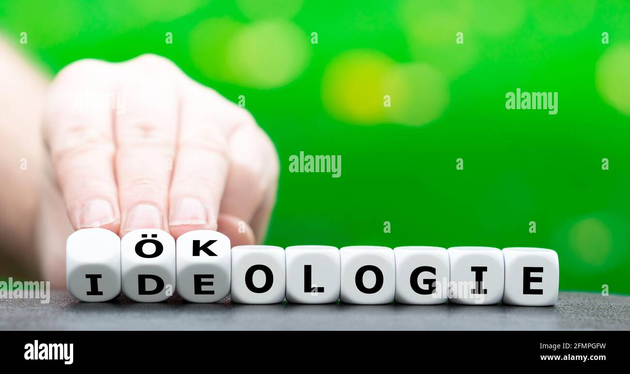 Die Hand dreht Würfel und ändert das deutsche Wort 'Ideologie' (Ideologie) in 'Ökologie' (Ökologie). Stockfoto