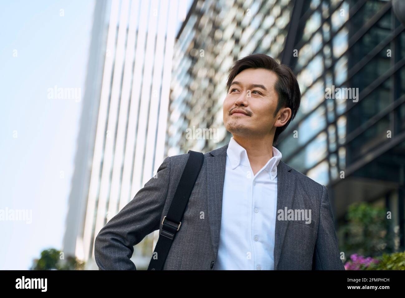 Erfolgreiche asiatische Corporate Executive zu Fuß im zentralen Geschäftsviertel von Moderne Stadt Stockfoto