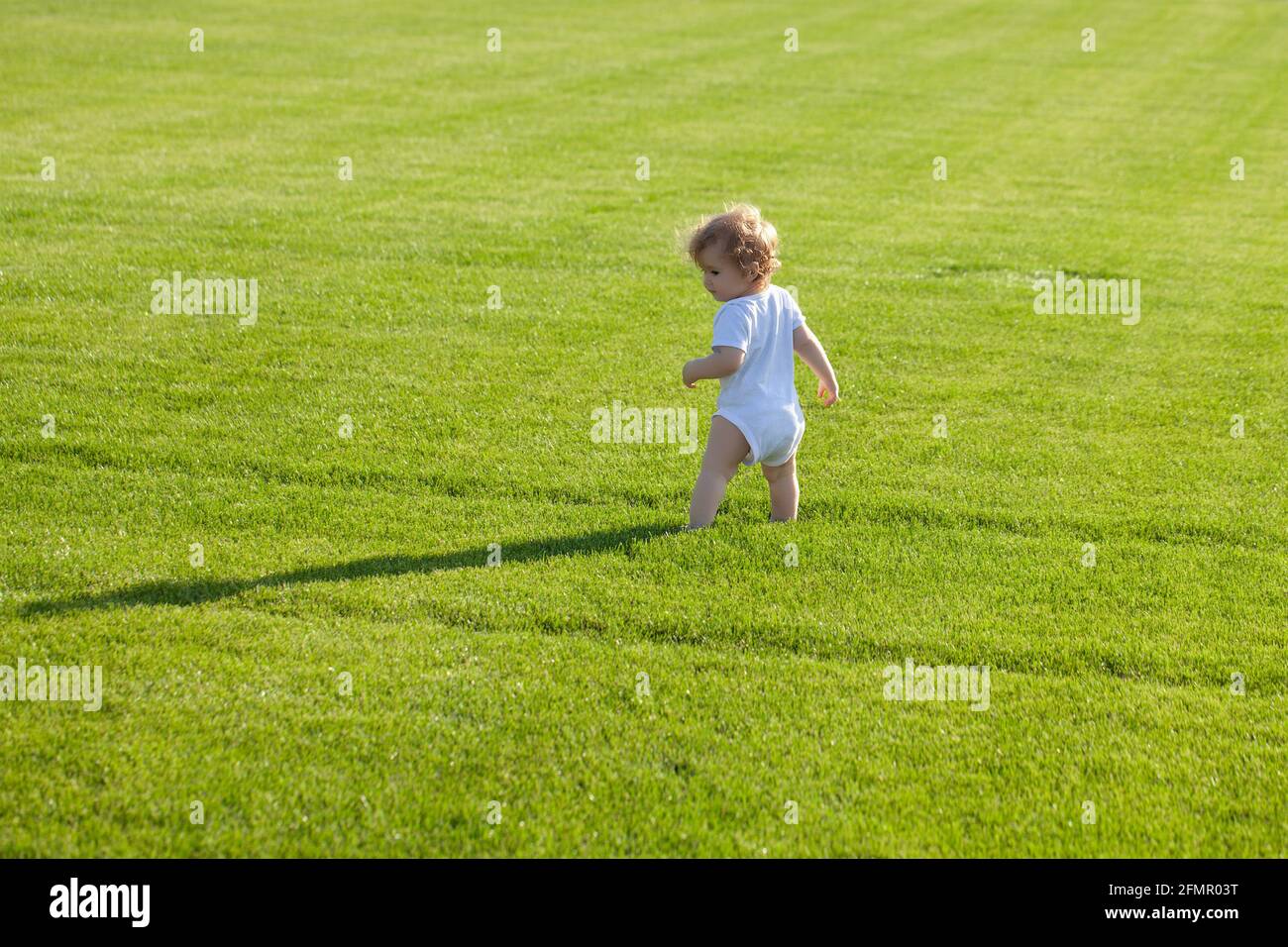 Rückansicht von glücklicher Kindheit und Kinderpflege. Baby in schönen Frühling grünen Feld. Stockfoto