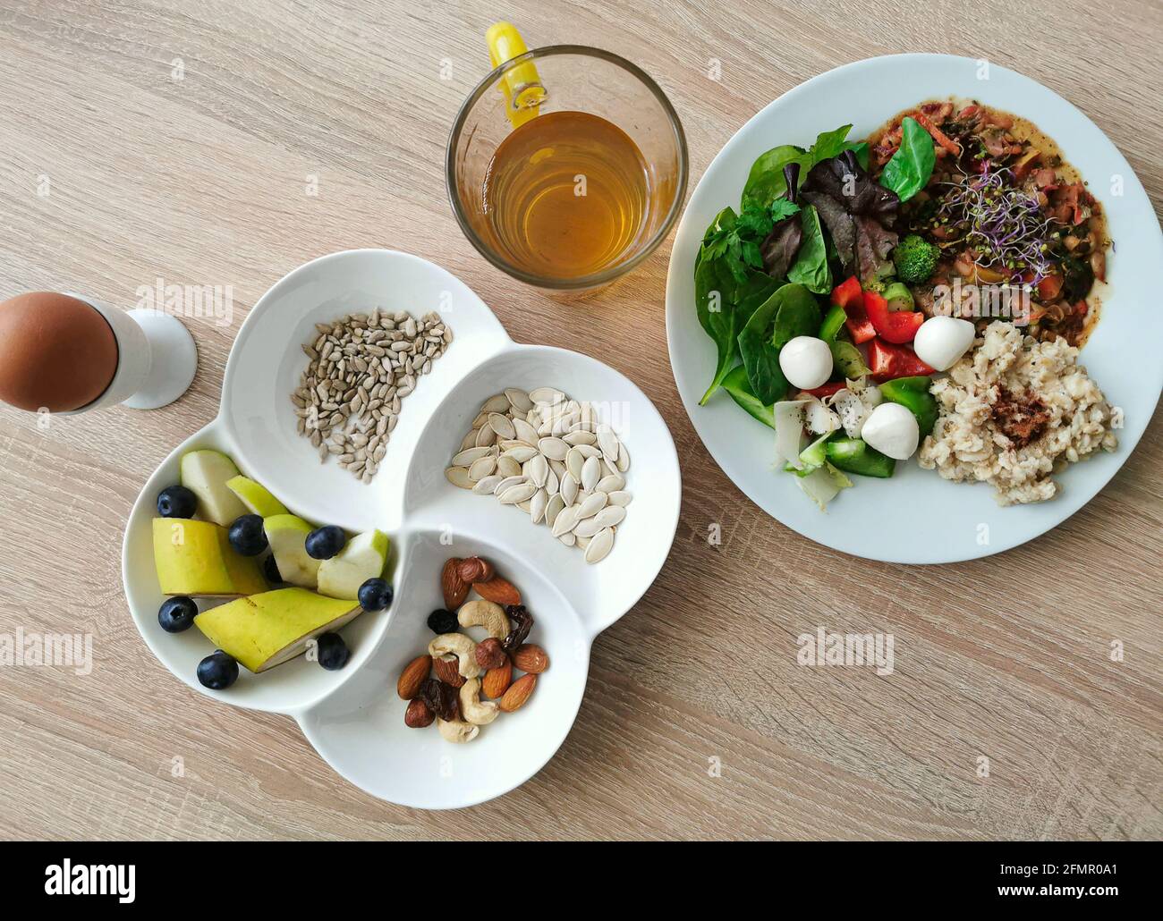 Ein gesundes, leckeres Frühstück mit Eiweiß, Fett und Kohlenhydraten. Weich gekochtes Ei. Haferflocken mit Zimt, Mocarella-Käse, gekochtem und rohem Gemüse Stockfoto