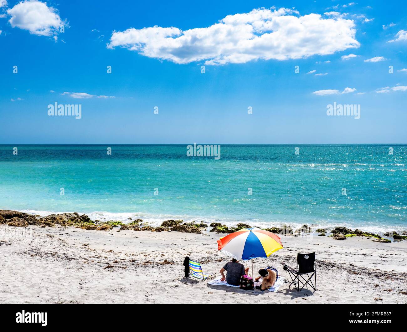 Pärchen entspannen sich im Urlaub unter einem Sonnenschirm auf dem Golf von Mexiko Strand in Venedig Florida USA Stockfoto