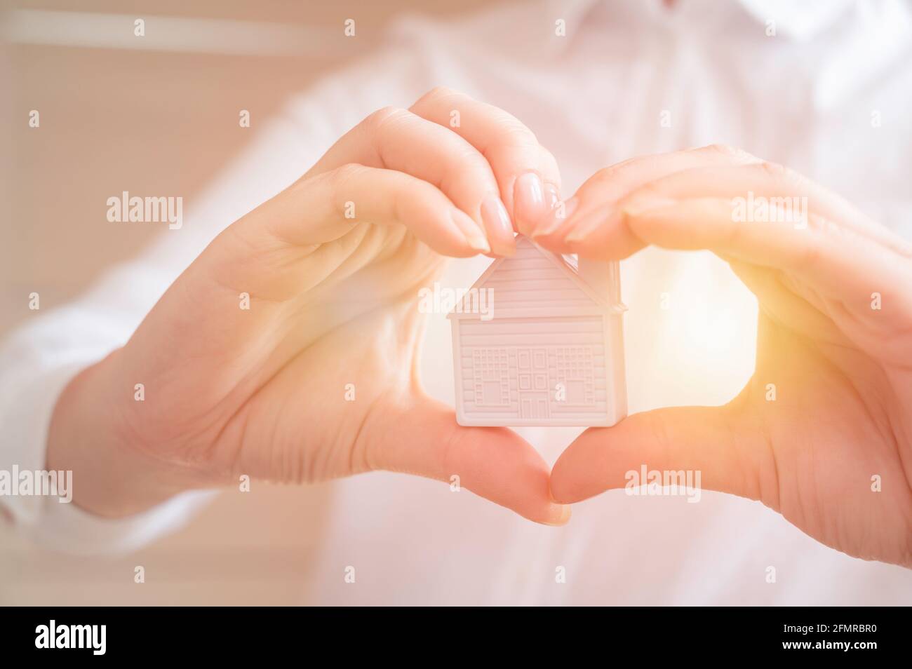 Hände halten Miniaturhaus. Wohnungs- und Hausschutz-Versicherungskonzept, Familienhaus, Hauskredit, Hausversicherung, Familienlebensversicherung Stockfoto