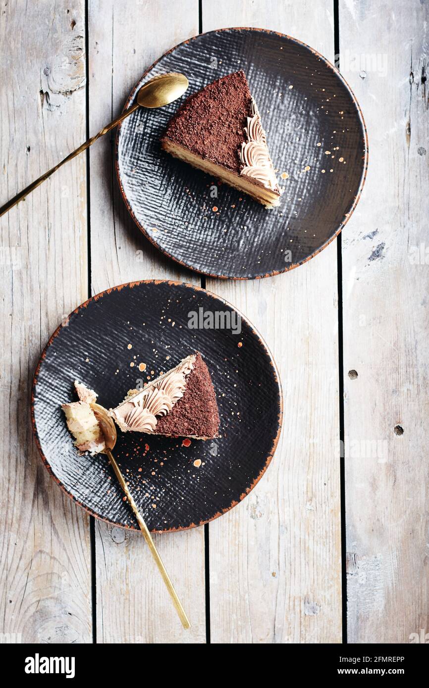Zwei Stück Schokoladenkuchen auf schwarzen Tellern, Draufsicht. Stockfoto