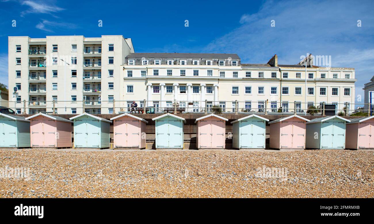 Strandhütten in Pastellfarben mit weißem Hotel in St. Leonards East Sussex Stockfoto